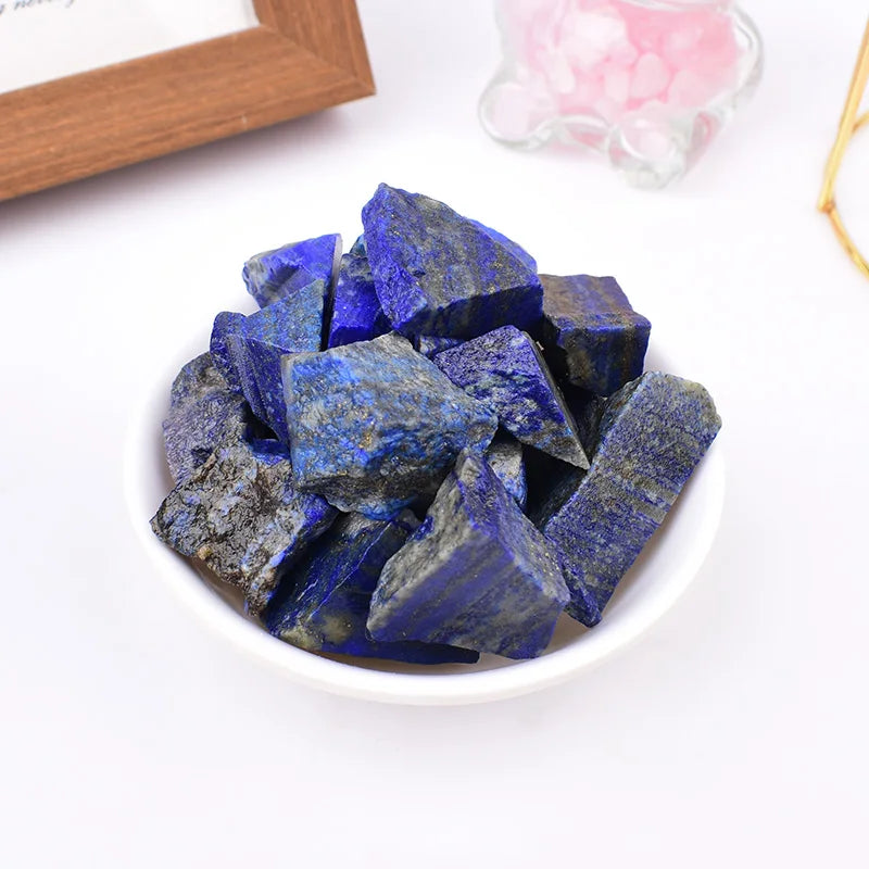 Rough Lapis Lazuli pieces piled in a white bowl in a styled setting.