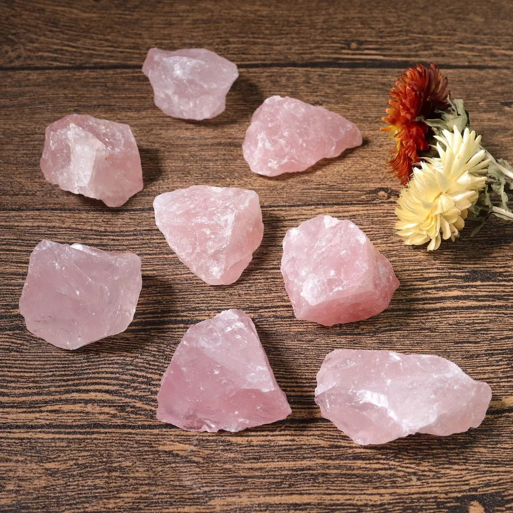 Assorted rough Rose Quartz chunks arranged on a wood tabletop.